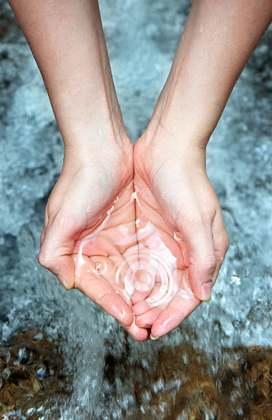 Woman taking clear water at a lake by hands